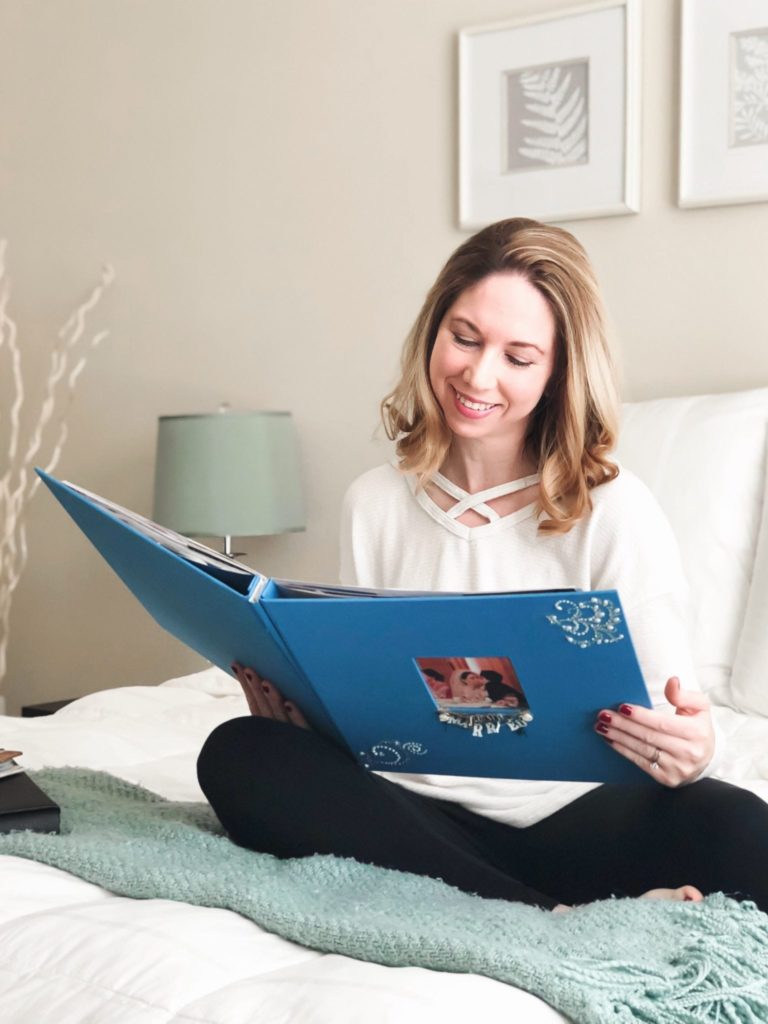 woman sitting on bed smiling while reading memory book