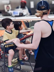 mom and kids in cart at seafood counter in grocery store