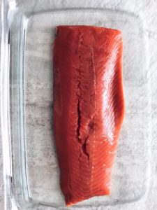 slab of raw salmon in glass dish