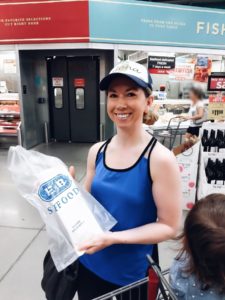 woman in grocery store holding bag of fresh salmon