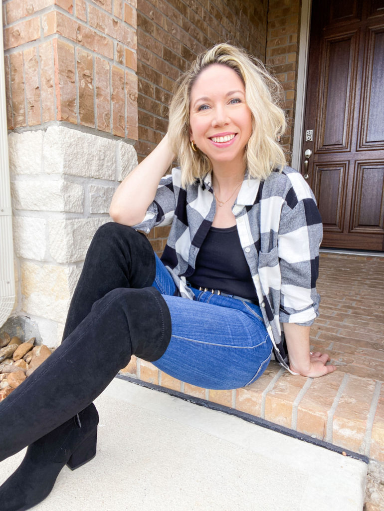 woman-sitting-posing-wearing-plaid-flannel-shirt-open-and-over-a-tank-top-with-jeans-and-over-the-knee-black-boots