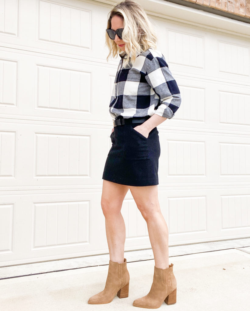 woman-standing-wearing-flannel-shirt-with-black-skirt-booties-and-black-sunglasses